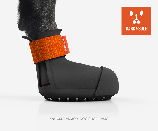 Knuckle armor dog shoe with orange strap and 'Bark & Sole' branding on a white background