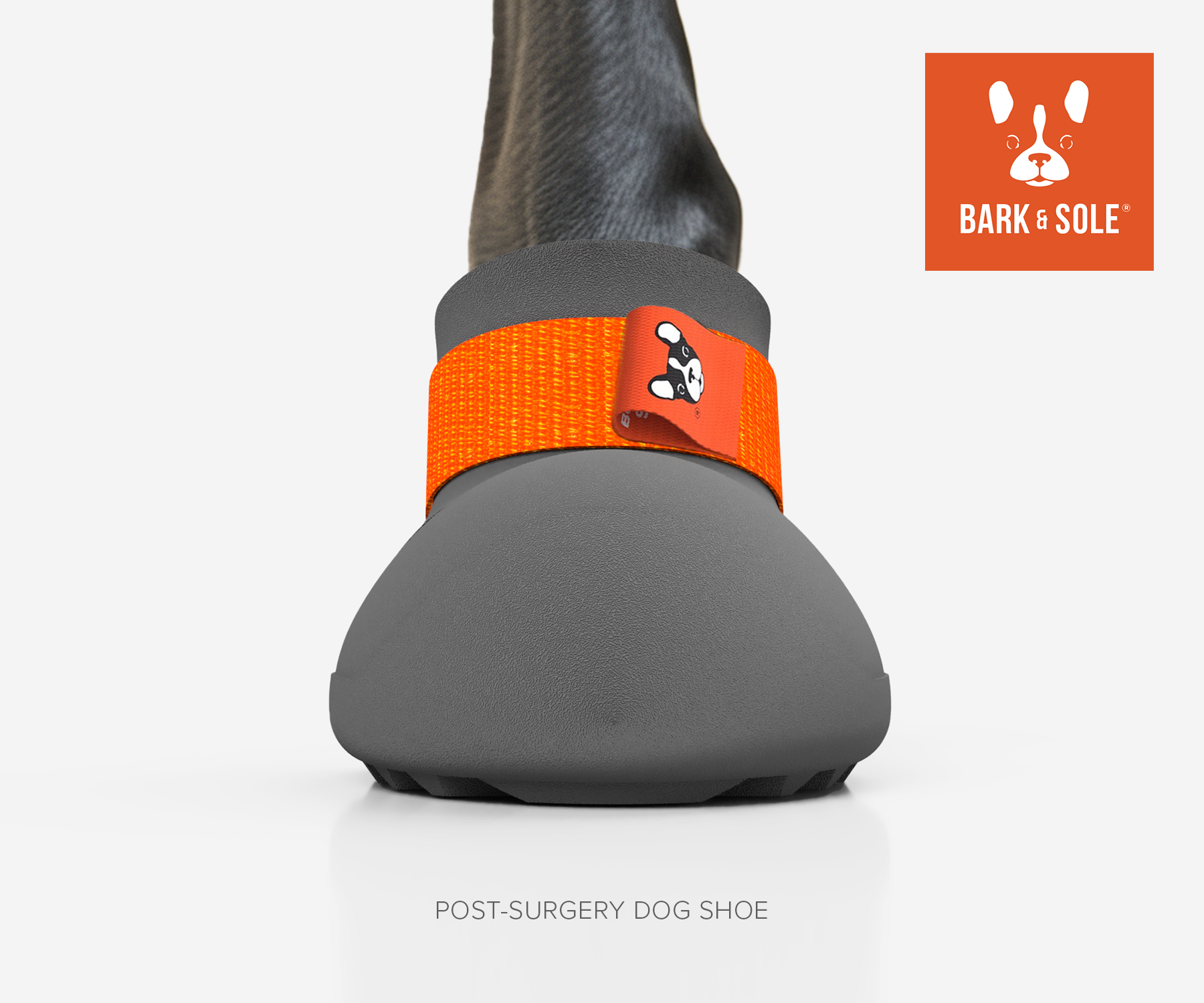 Gray post-surgery orthopedic dog shoe with orange strap and 'Bark & Sole' logo on a white background