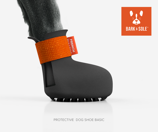 Protective dog shoe with orange strap on a white background, featuring the Bark & Sole logo.